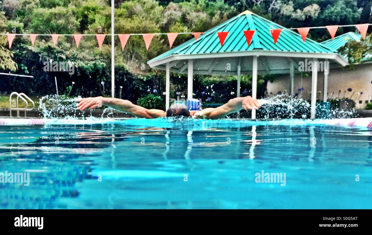 Muscular athlete swimming butterfly, water level view. HDR. - Smartphone Captured Stock Image