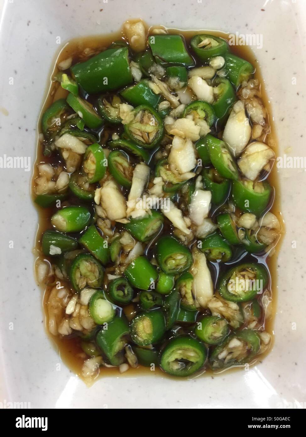 Top view of mixed cut green chillies and garlic in soya sauce - Smartphone Captured Stock Image
