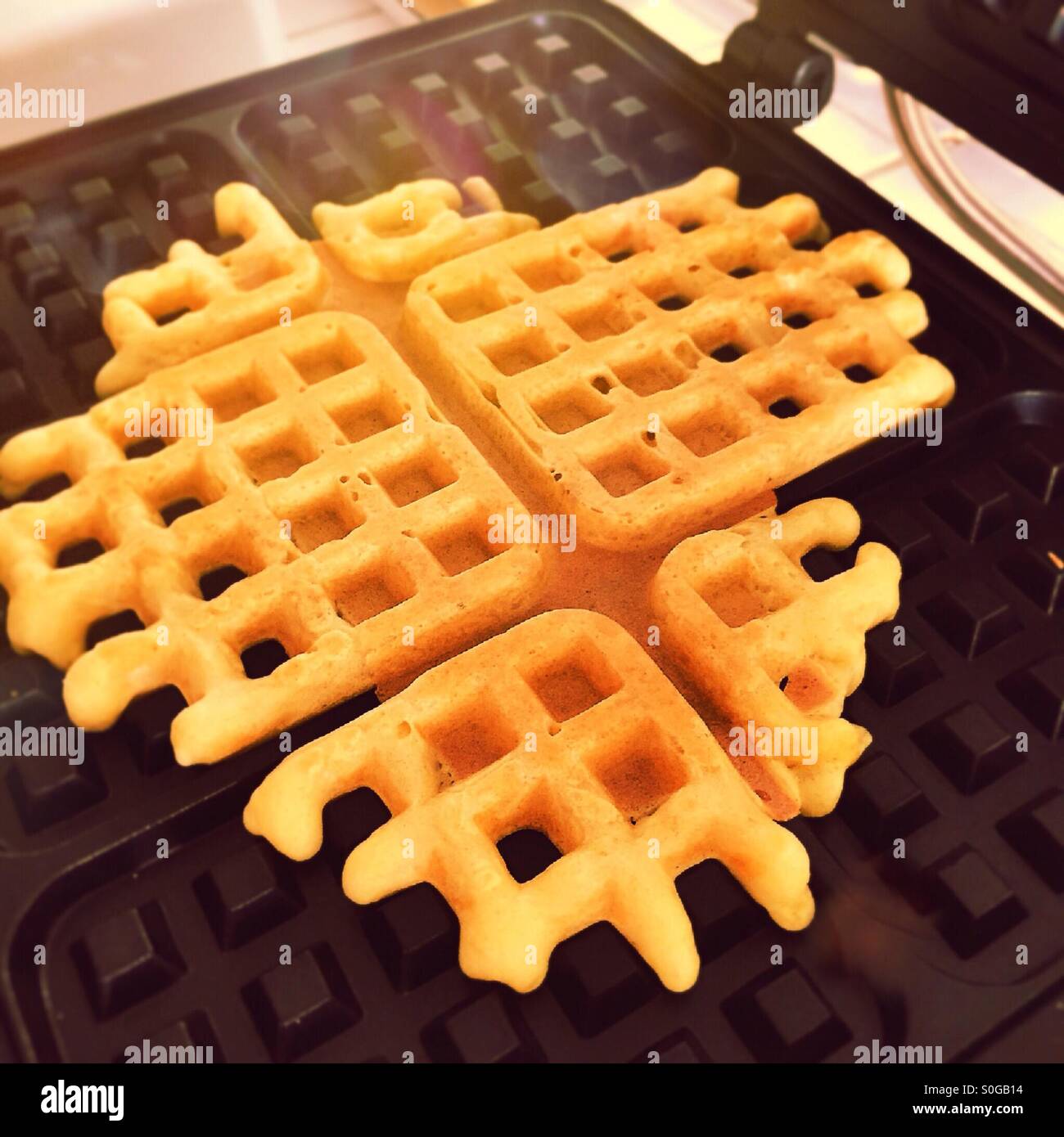 waffles cooking on a waffle iron Stock Photo Alamy