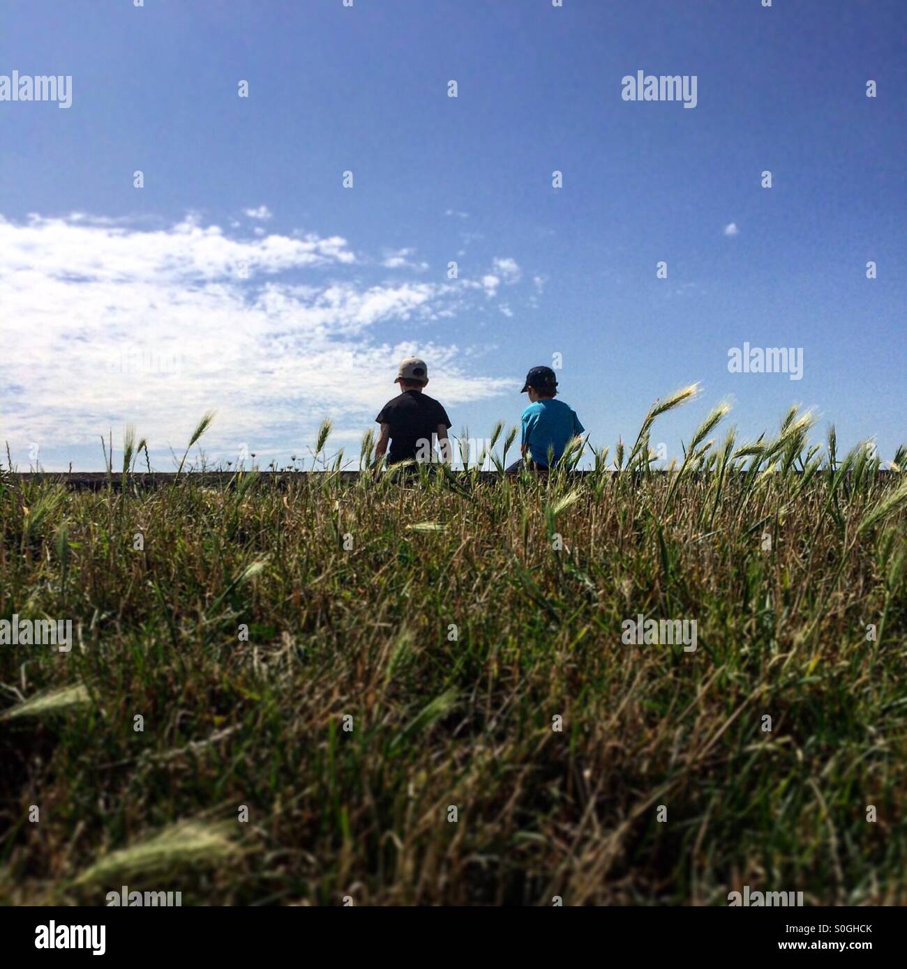 Boys sitting on wall looking at hidden view - Smartphone Captured Stock Image