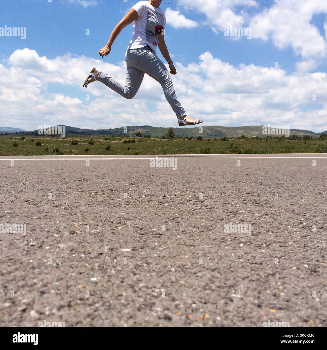 Woman jumping with no head on the picture on an empty road - Smartphone Captured Stock Image