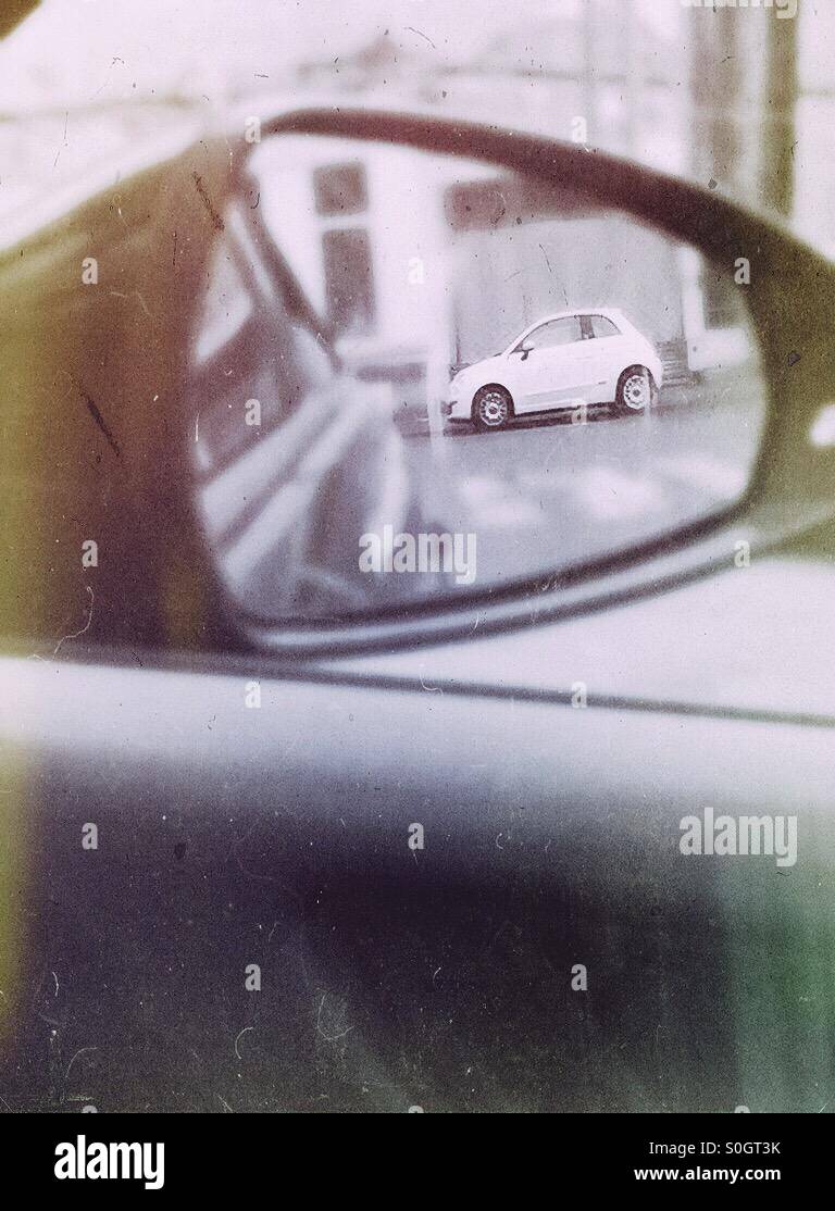 Small white car seen through a rear view mirror - Smartphone Captured Stock Image