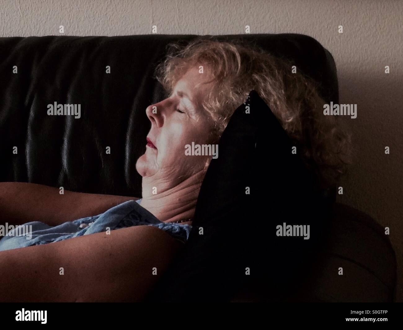 Mature woman sleeping on couch Stock Photo