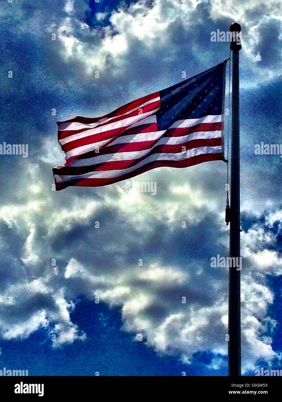 American flag being blown by wind, with blue sky and white clouds - Smartphone Captured Stock Image