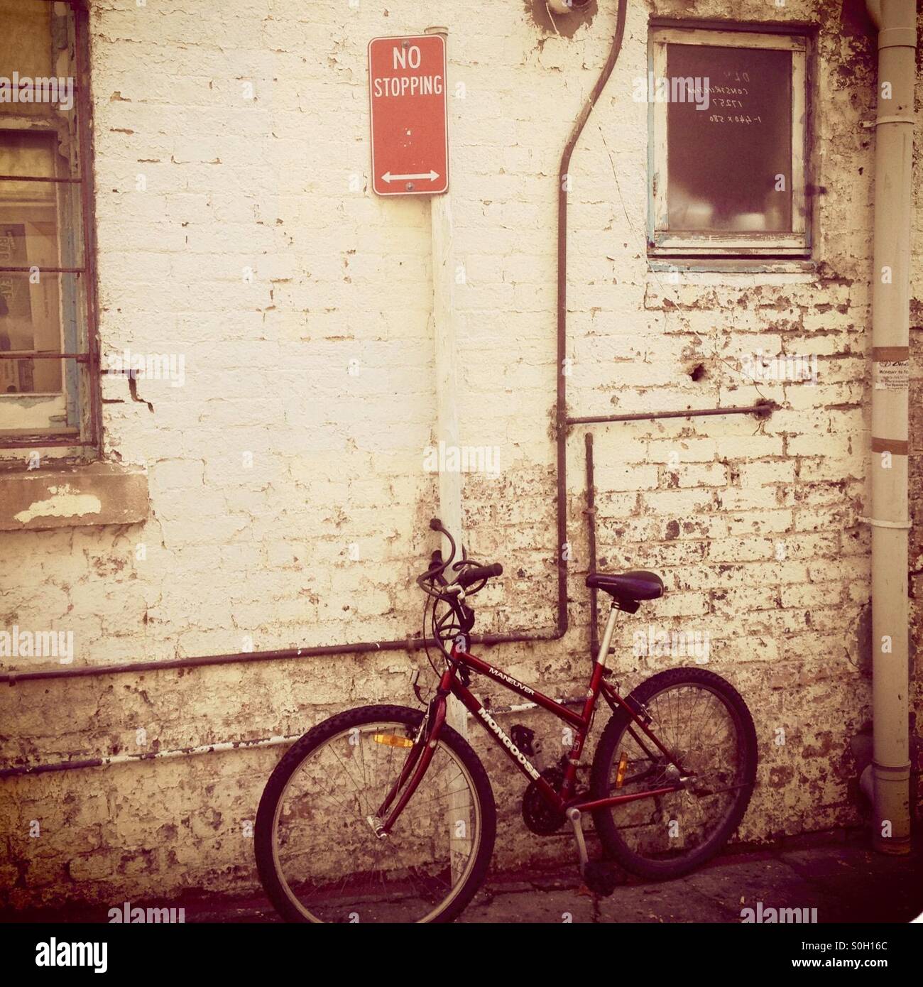 A semi sepia toned image of an old bicycle parked in a back laneway under a No Stopping sign in Sydney, Australia - Smartphone Captured Stock Image A semi sepia toned image of an old bicycle parked in a back laneway under a No Stopping sign in Sydney, Australia - Smartphone Captured Stock Image