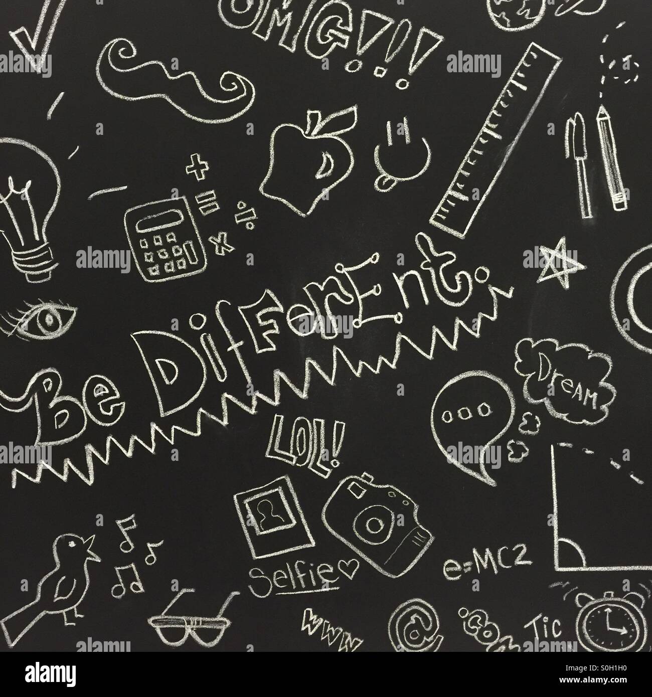 Drawing and writing on a black chalk board - be different, OMG, selfie, dream, and other pop culture references Stock Photo