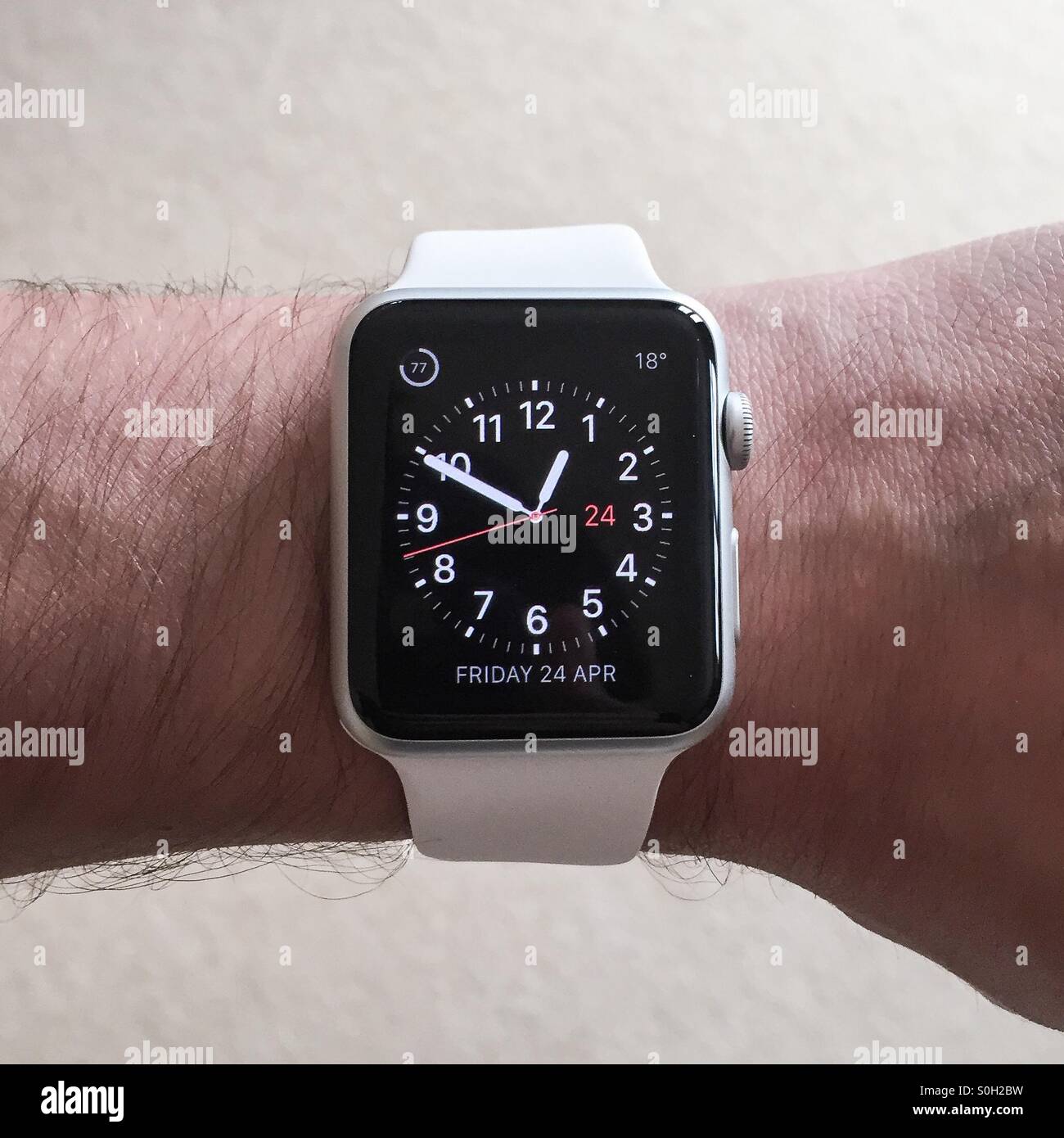 The Apple Watch white, sport, smartwatch shown top down on the wrist being activated to show the time in utility view Stock Photo