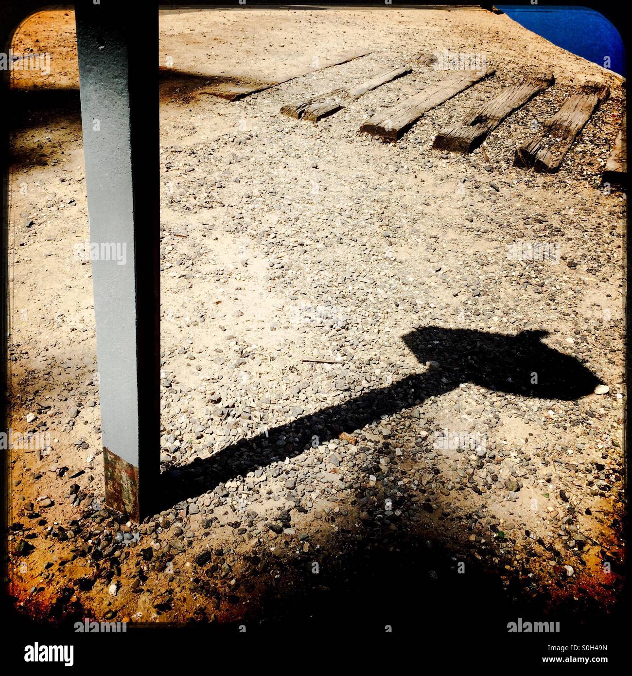 Shadow of a stop sign on a dirt road at an old railroad crossing. - Smartphone Captured Stock Image