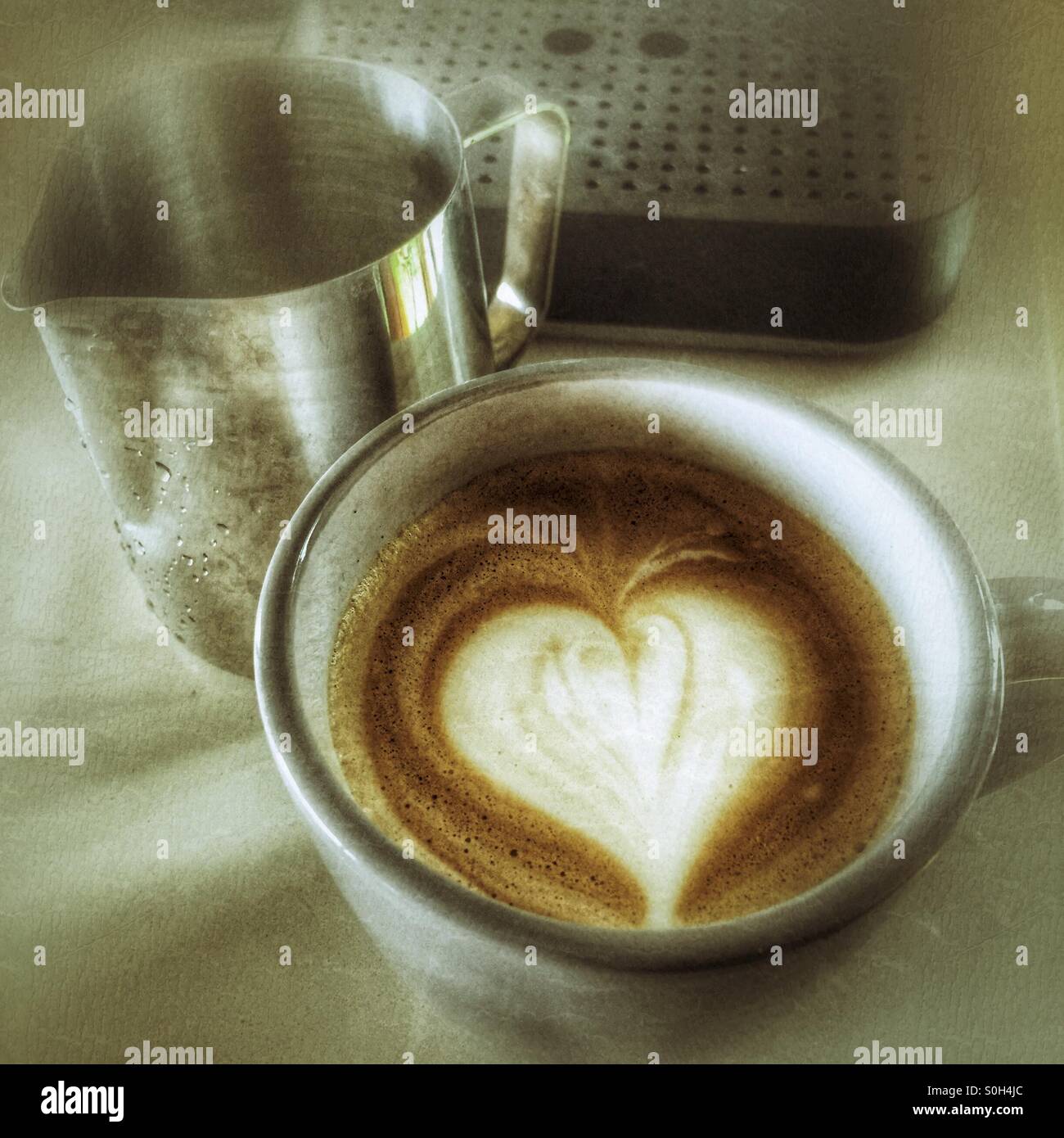 Cup of latte next to an espresso machine and a pitcher - Smartphone Captured Stock Image