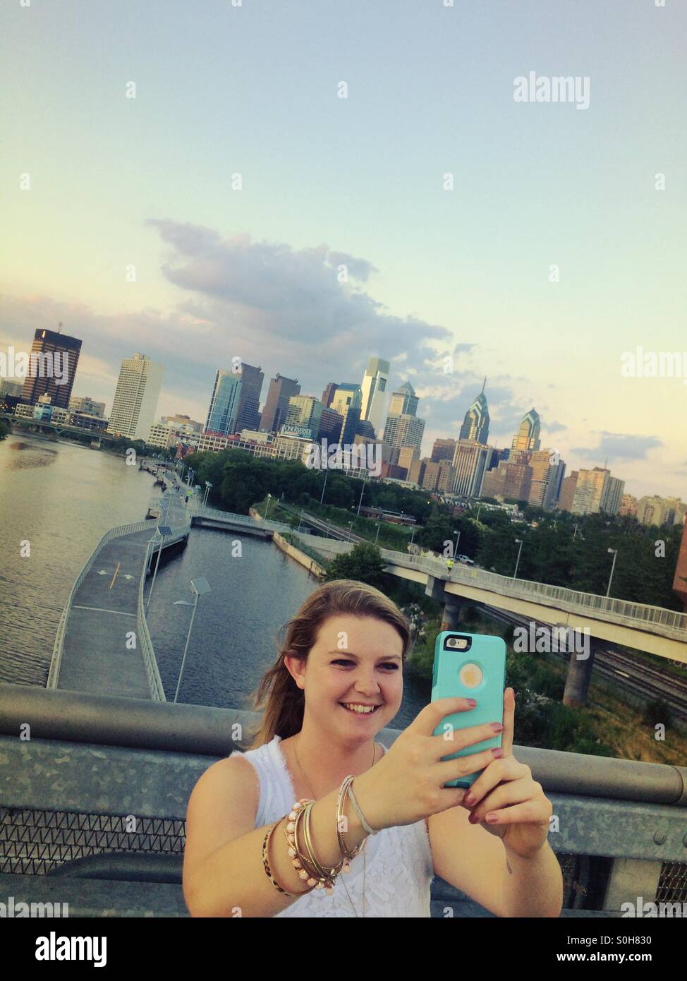 Girl with Schuylkill River Boardwalk and Philadelphia skyline in background taking selfie Stock Photo
