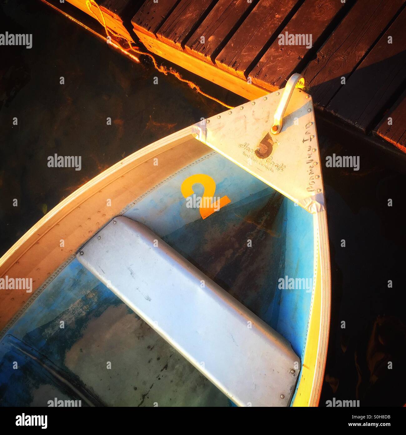 Bow of blue and yellow wooden boat number 2 tied up to dock Stock Photo