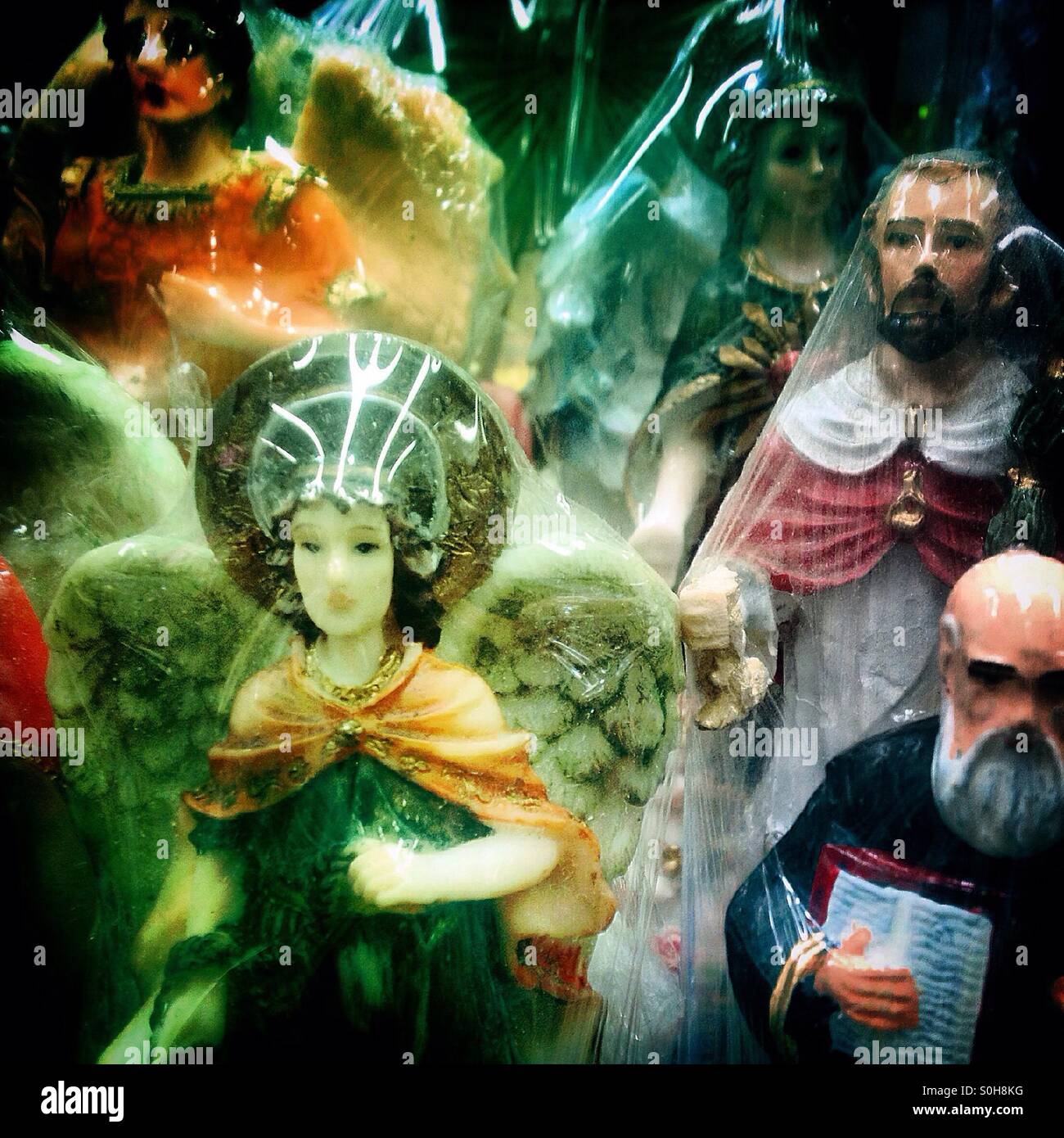Saints covered by plastic for sale in Mercado de Medellin market, Colonia Roma, Mexico City, Mexico - Smartphone Captured Stock Image