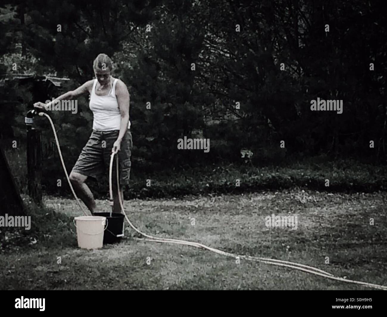 Woman filling bucket with water Stock Photo Alamy