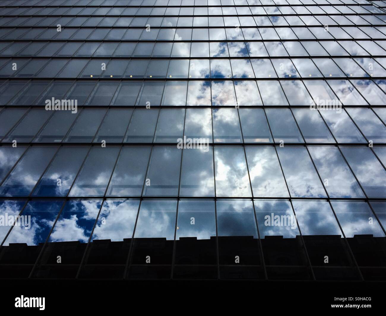 Clouds reflected in modern office block's glass wall - Smartphone Captured Stock Image