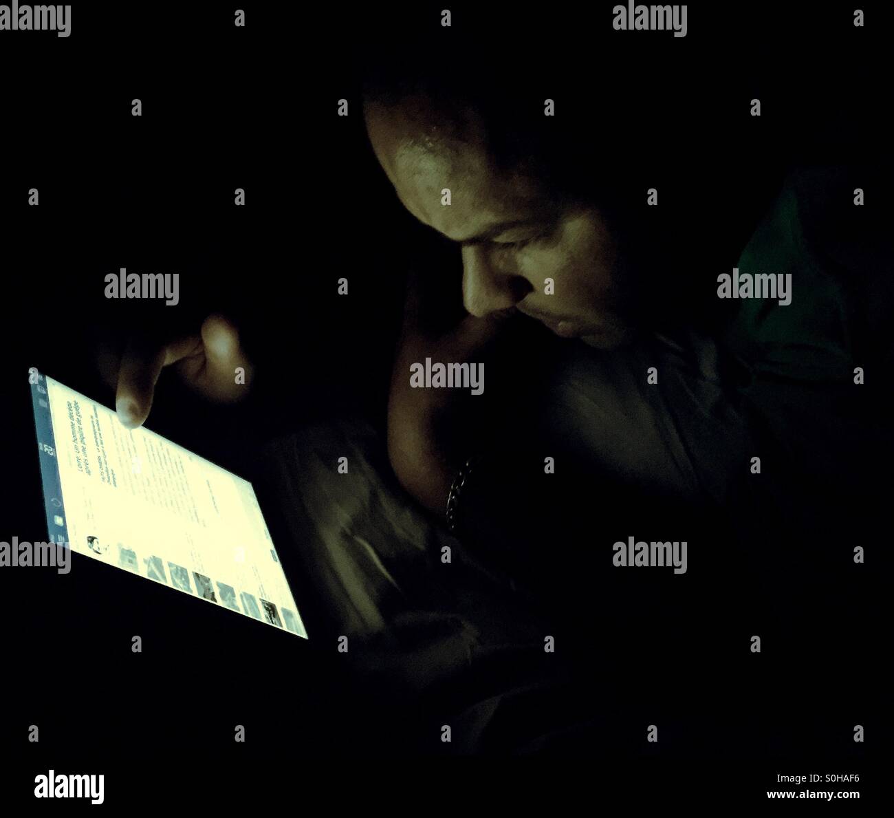 Man reading on his iPad at night - Smartphone Captured Stock Image