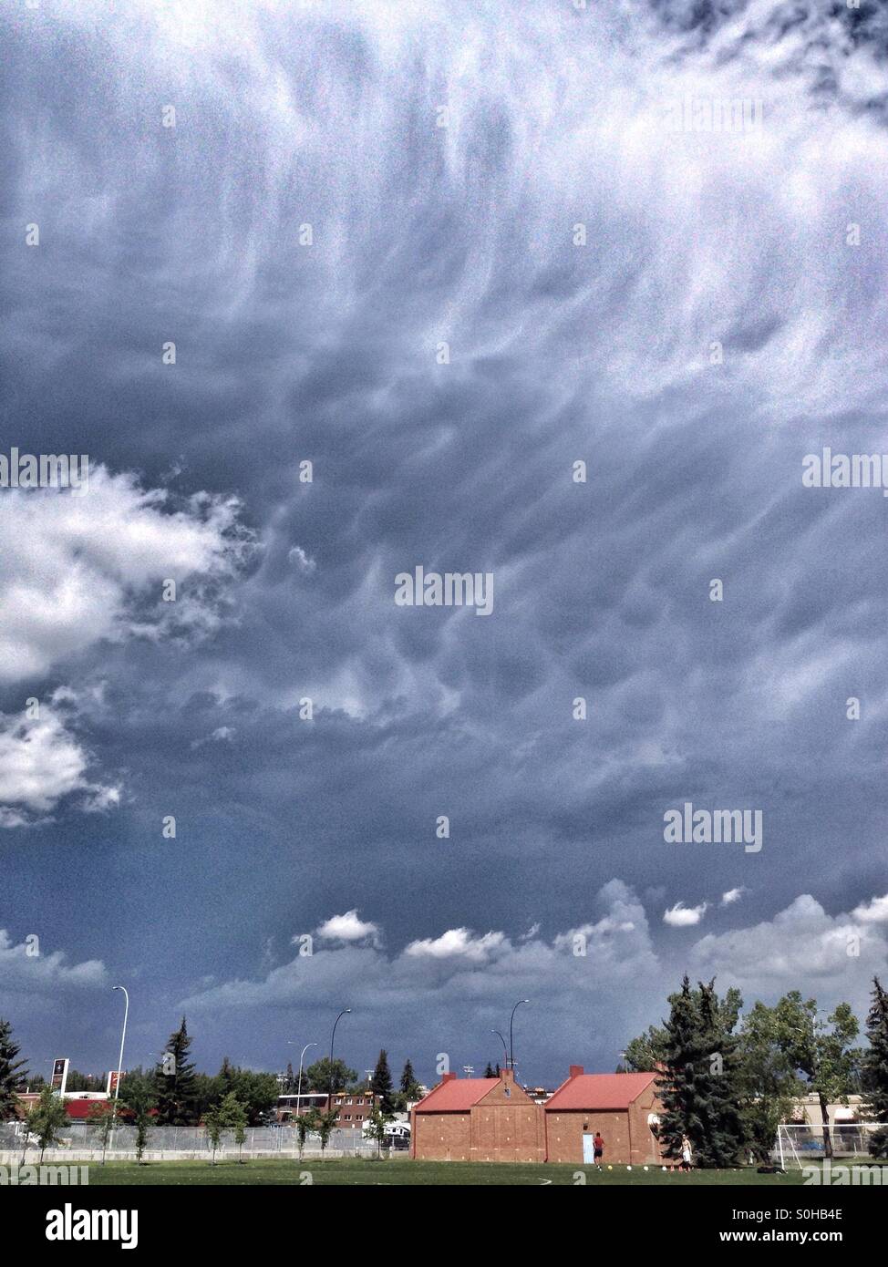 Large Cumulonibus storm cloud approaching a sports field, in Calgary, Alberta, Canada. July 2015. - Smartphone Captured Stock Image
