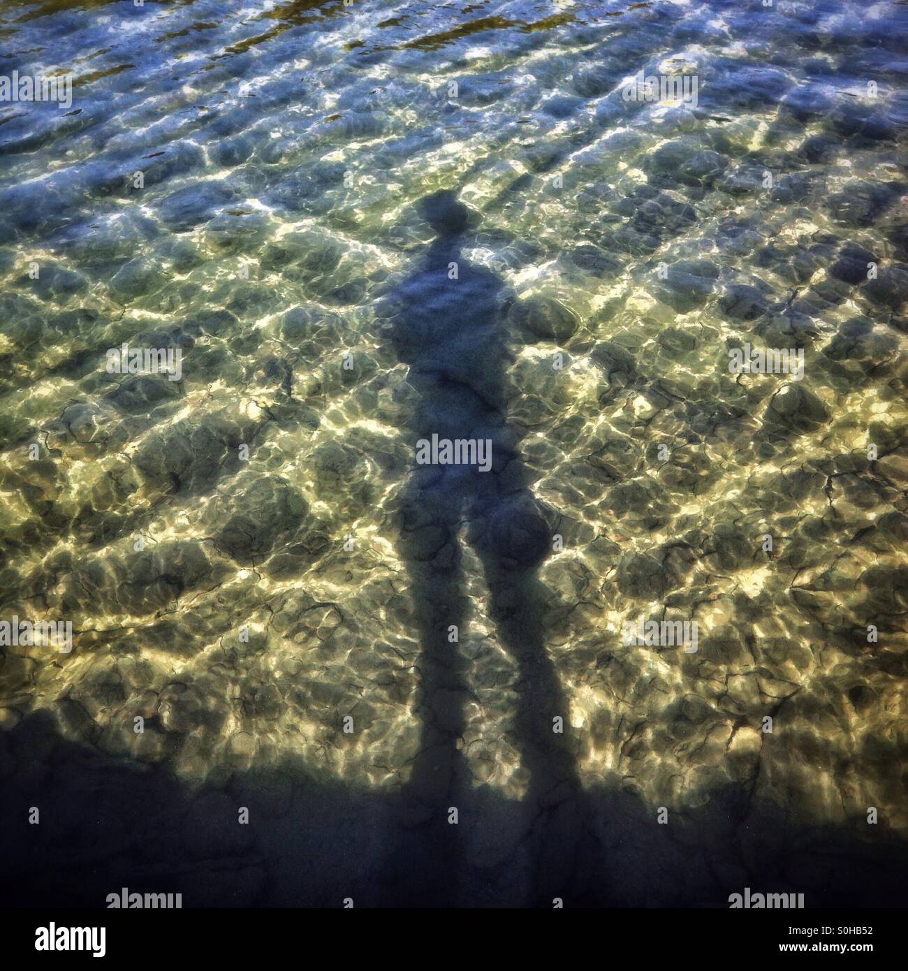 Shadow of a person standing by the edge of a lake. Cameron Lake, Waterton Lakes National Park, Alberta, Canada. - Smartphone Captured Stock Image
