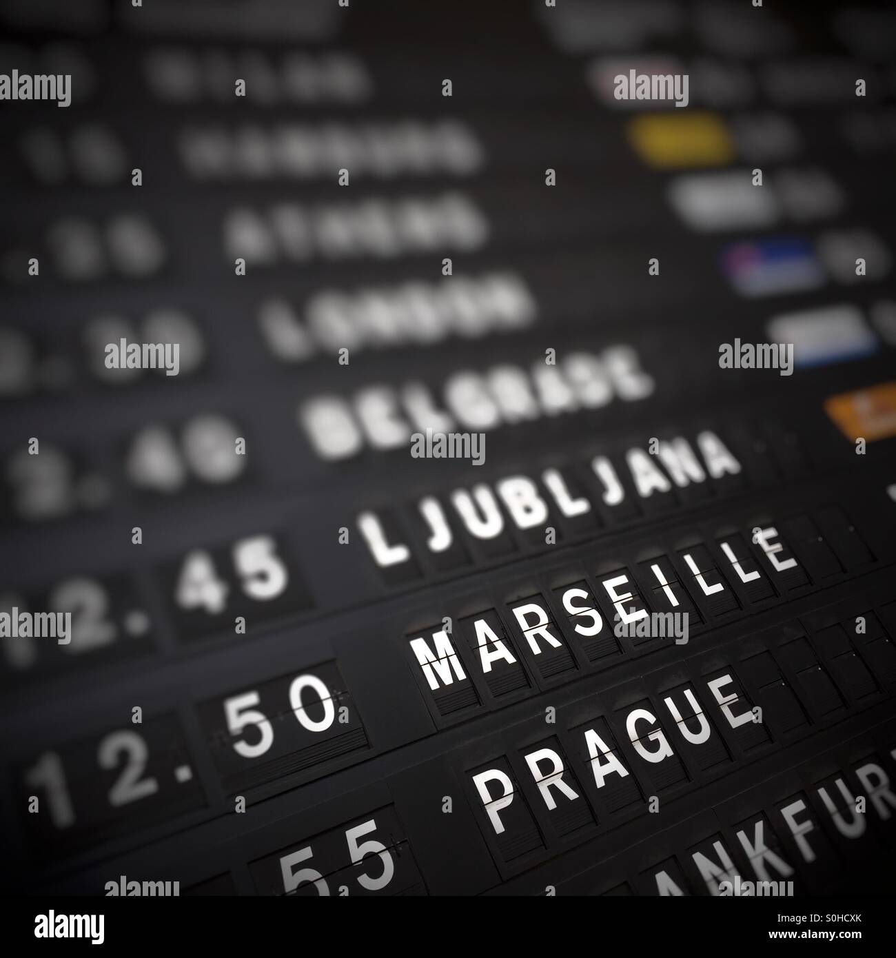 A flight departure board shows flight times for European cities such as Marsielle, Prague, and Belgrade. Stock Photo