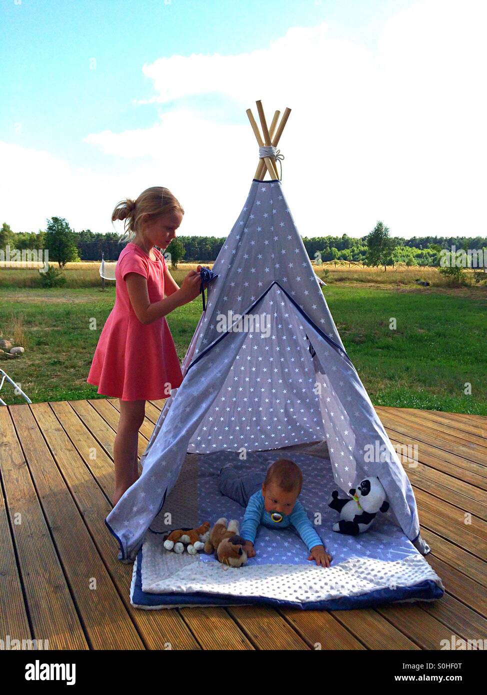 Siblings playing outside in teepee Stock Photo