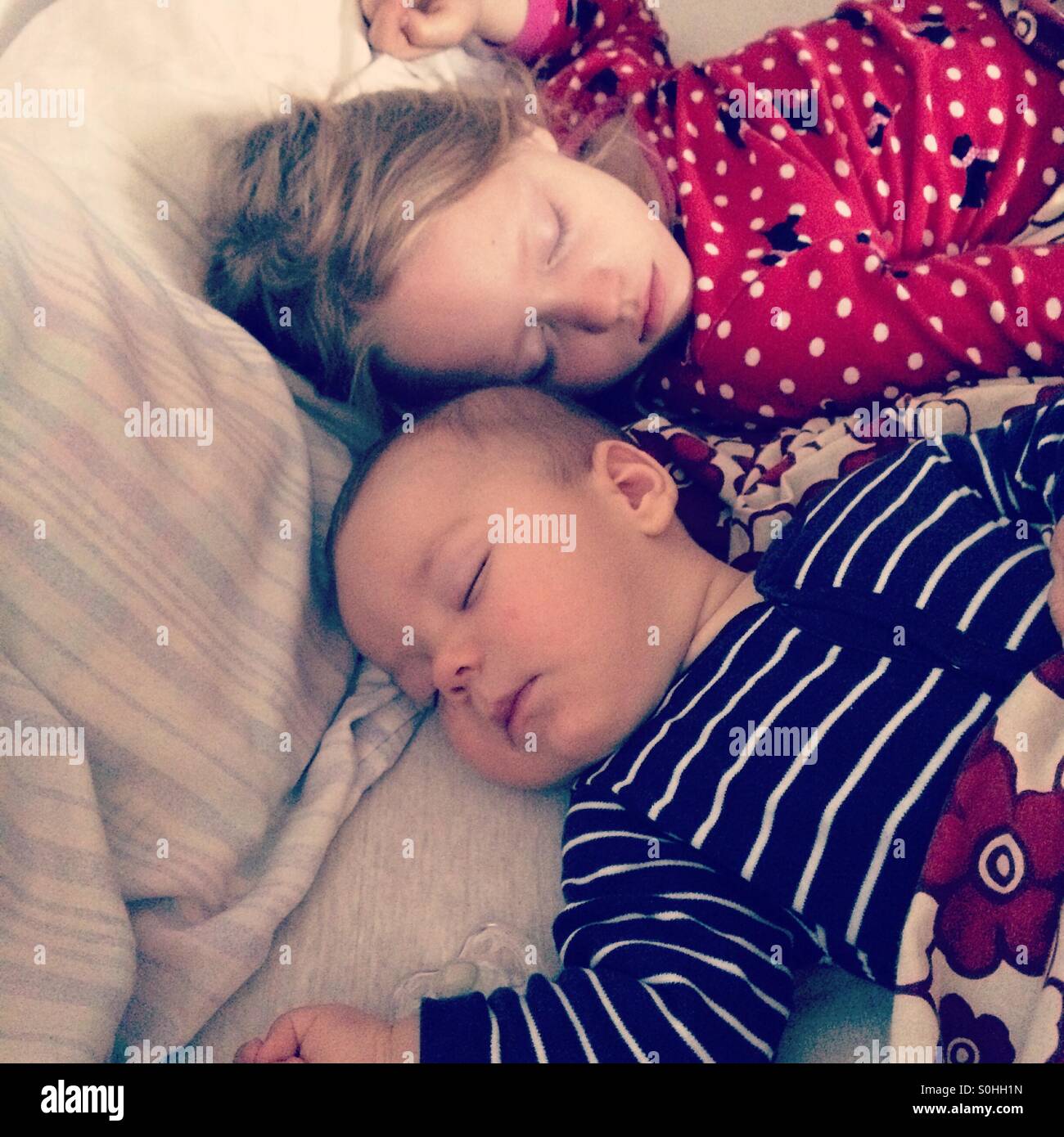 Two children sleeping peacefully together on parent's bed Stock Photo