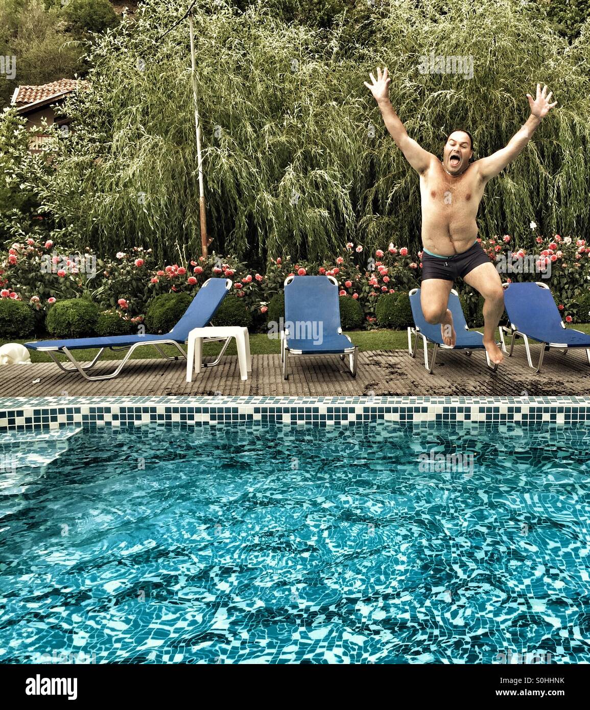 Man jumping into a swimming pool Stock Photo