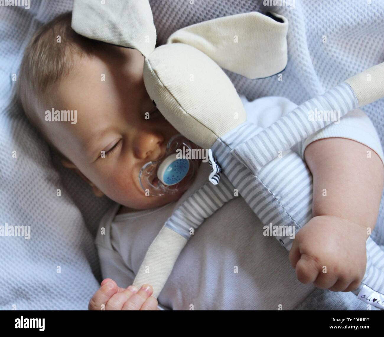 Baby boy sleeping with his bunny toy Stock Photo