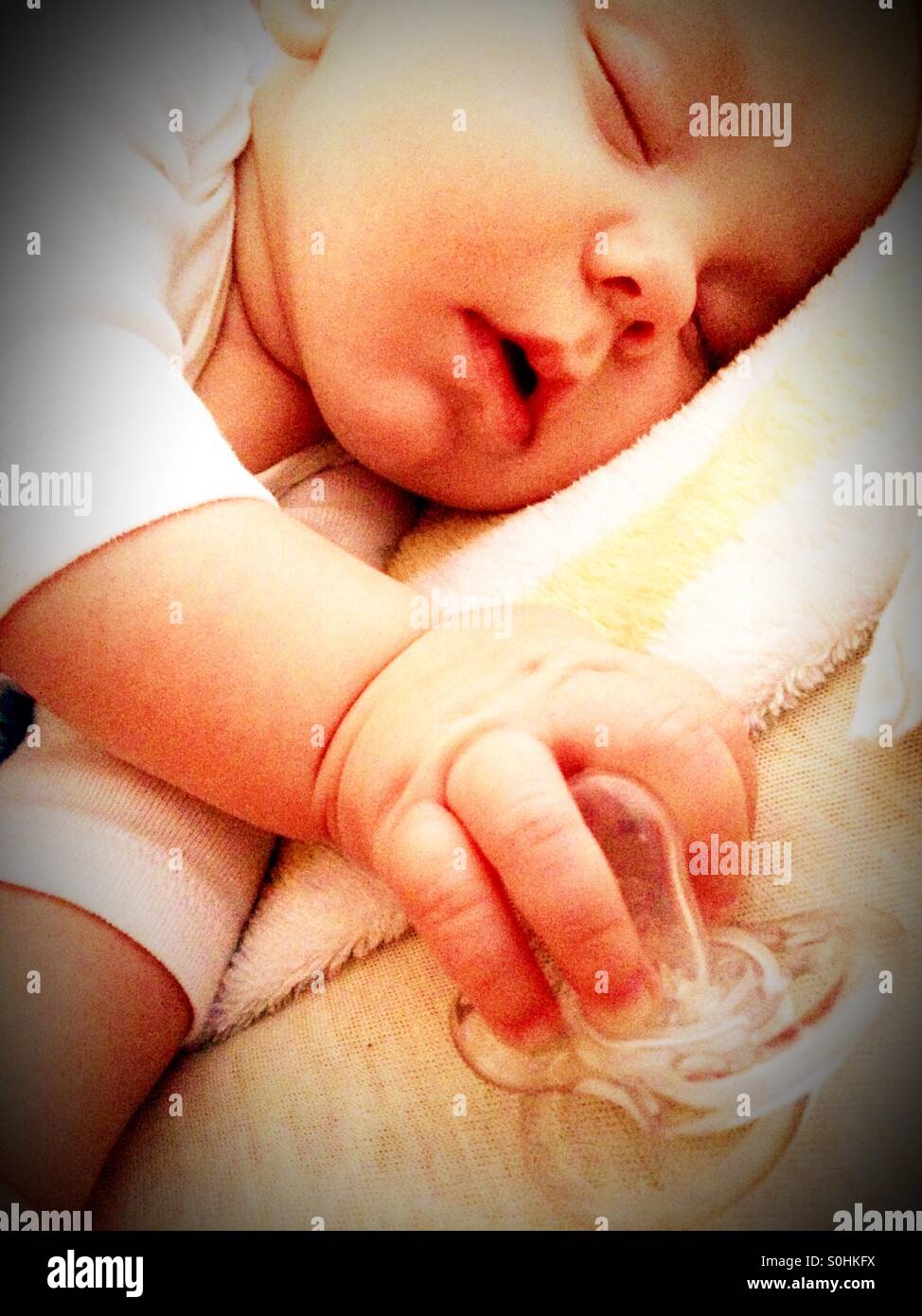 Sleeping baby boy holding his pacifier Stock Photo