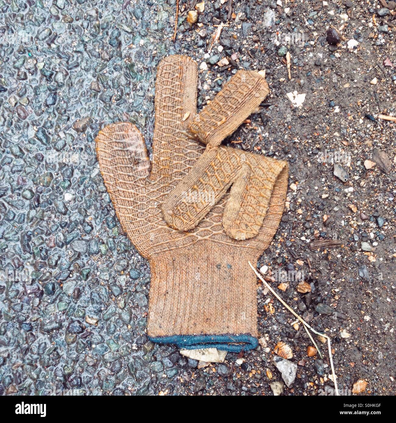 Discarded rubber coated glove in the shape of the peace sign or victory sign. - Smartphone Captured Stock Image