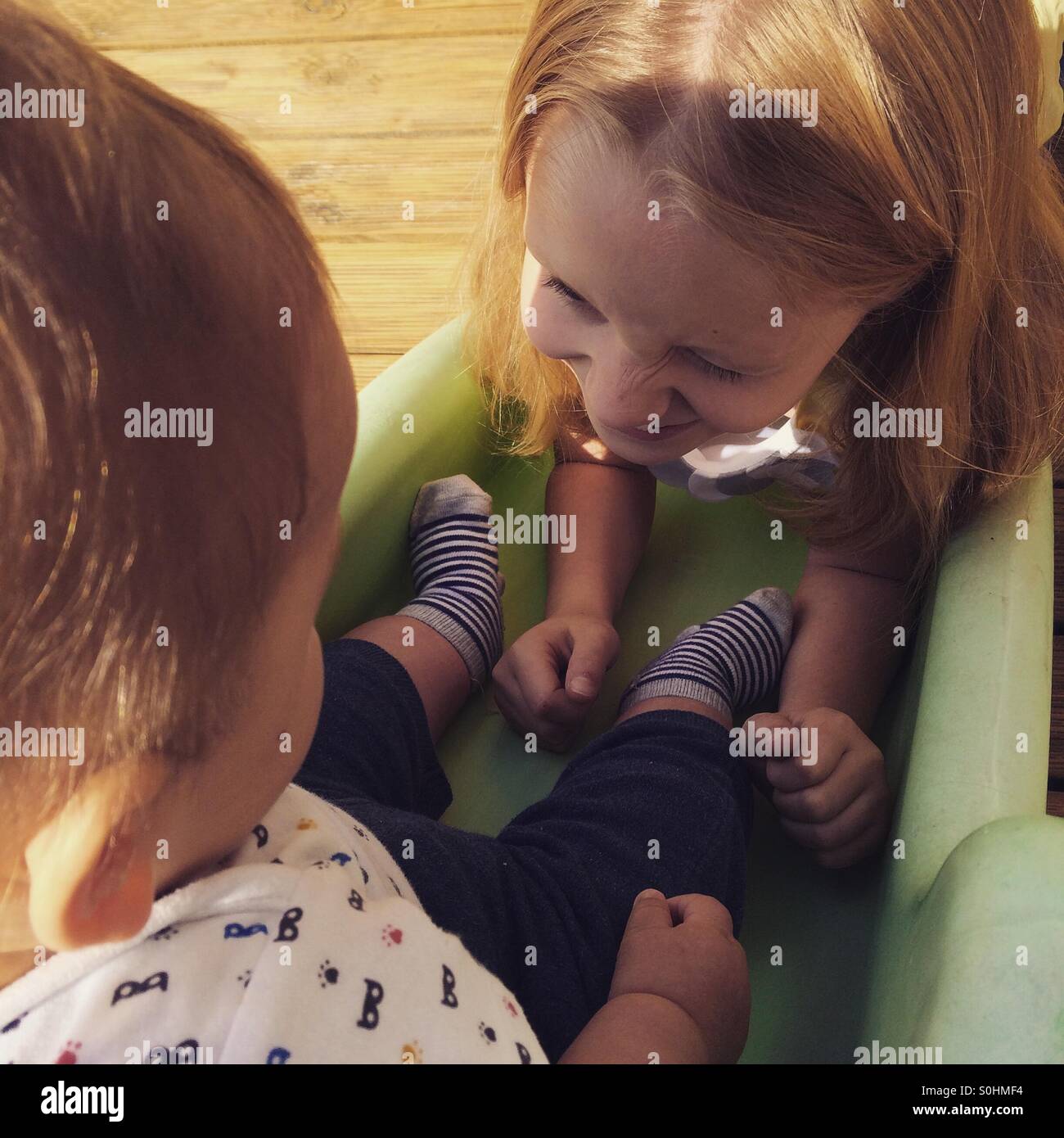 Girl helping her baby brother on a slide Stock Photo