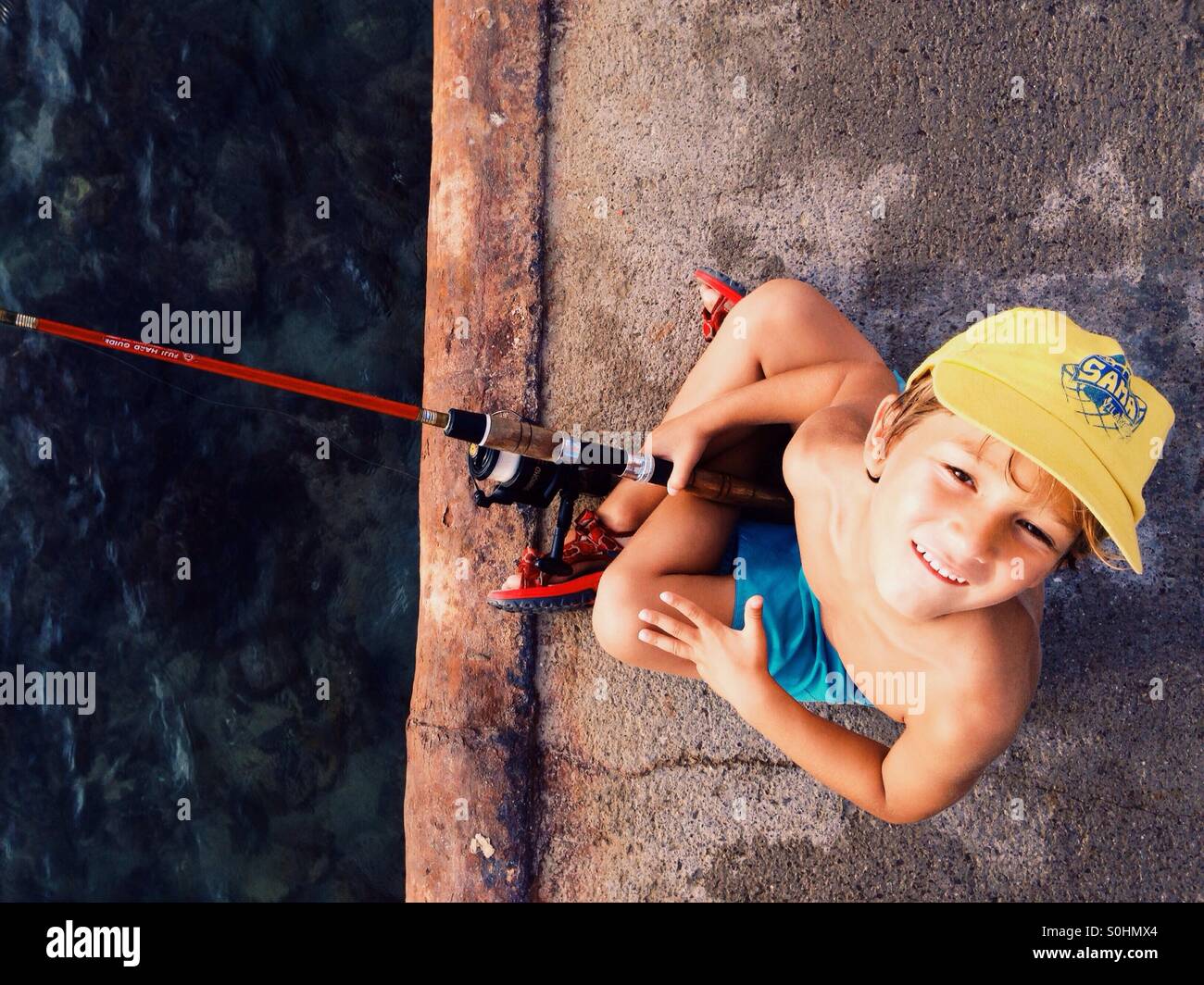 Boy fishing on a harbour Stock Photo