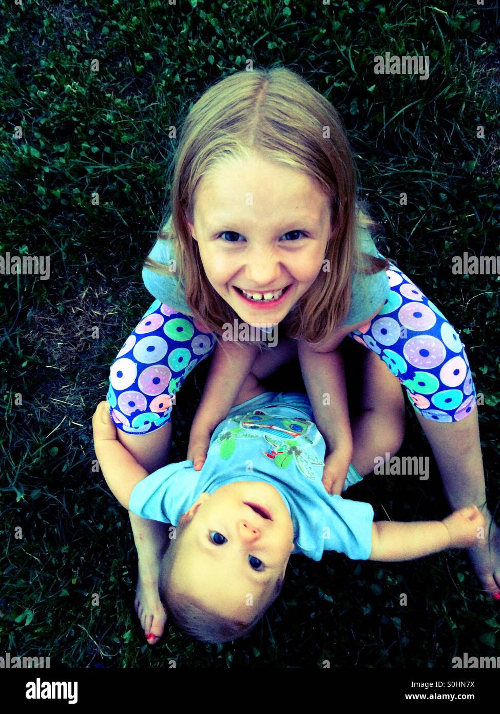 Smiling siblings sitting together o the grass Stock Photo