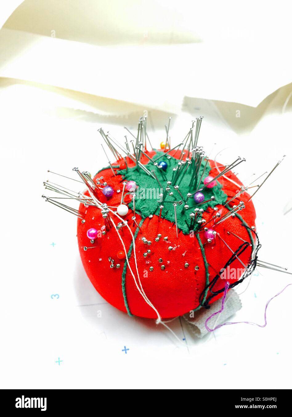 Pincushion in the shape of a red tomato is filled with pins - Smartphone Captured Stock Image