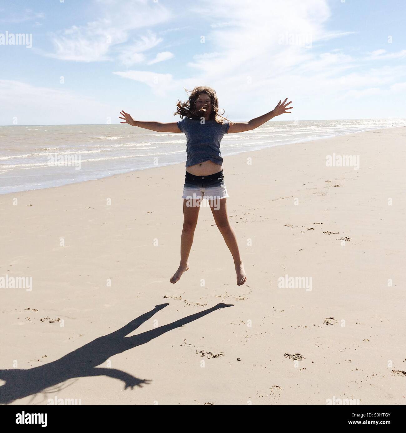 Girl, jumping on Winchelsea beach, East Sussex, UK Stock Photo