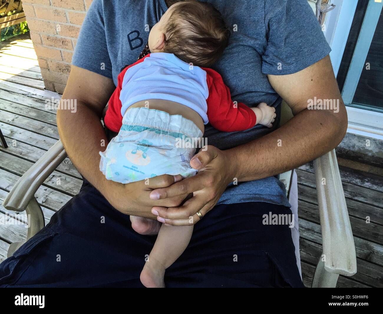 Fatherhood. A baby, a few weeks old, snuggles peacefully in dad’s embrace, Ontario, Canada. Concepts: two generations, contact, comfort zone, warmth, hand held. Father and child - Smartphone Captured Stock Image