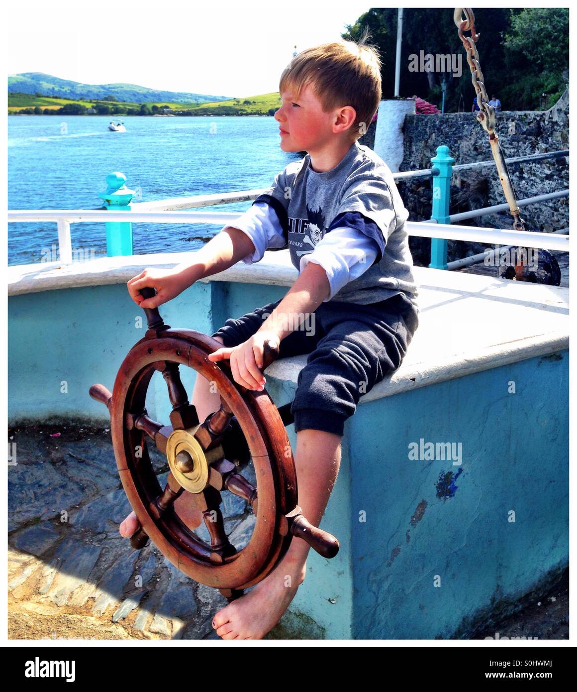 Boy steering a boat. Stock Photo