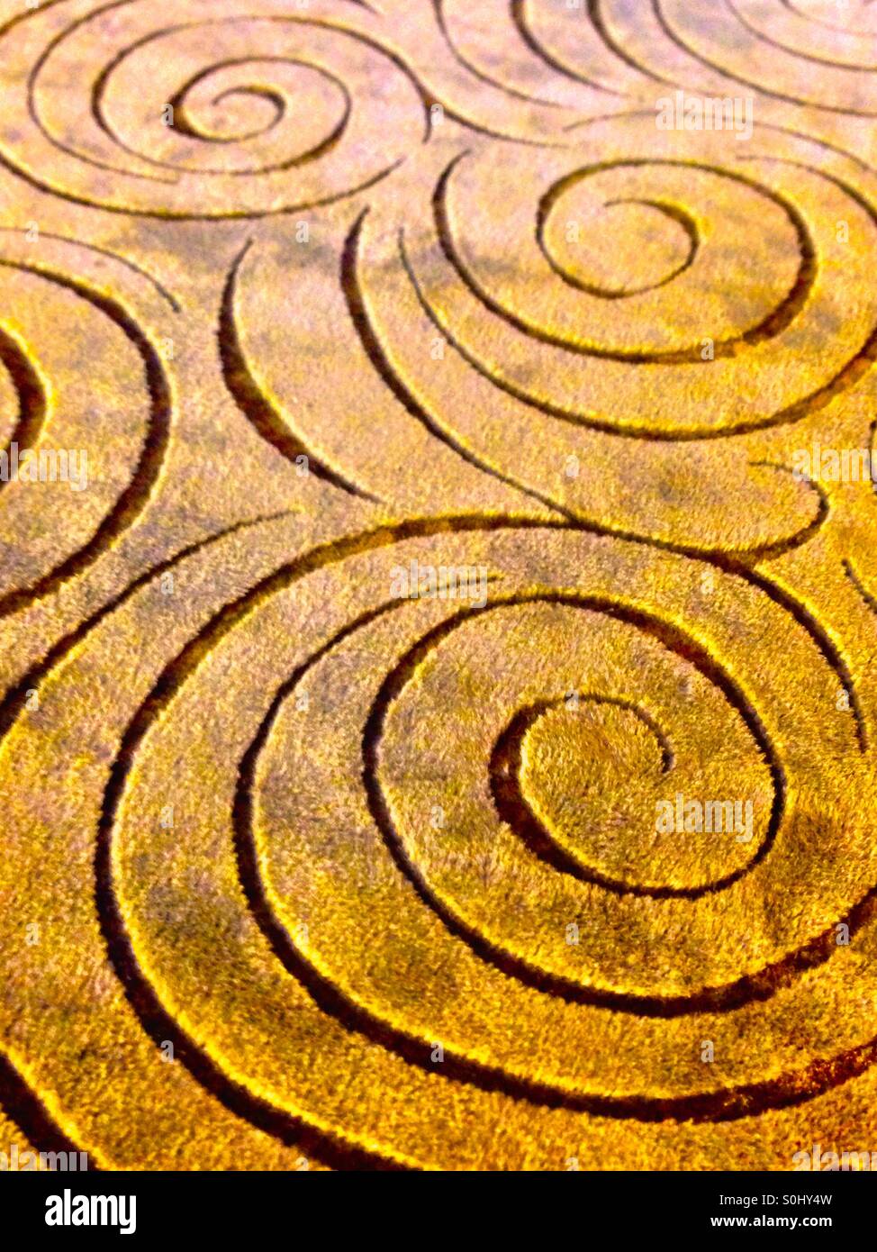 Spiral patterns engraved in a brown background - Smartphone Captured Stock Image