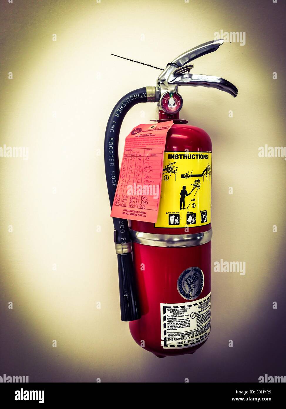 Fire focus. A directional spotlight focuses on the fire extinguisher attached to the wall, Ontario, Canada. Concepts:readiness, safety, prevention, proactive, pointer. - Smartphone Captured Stock Image
