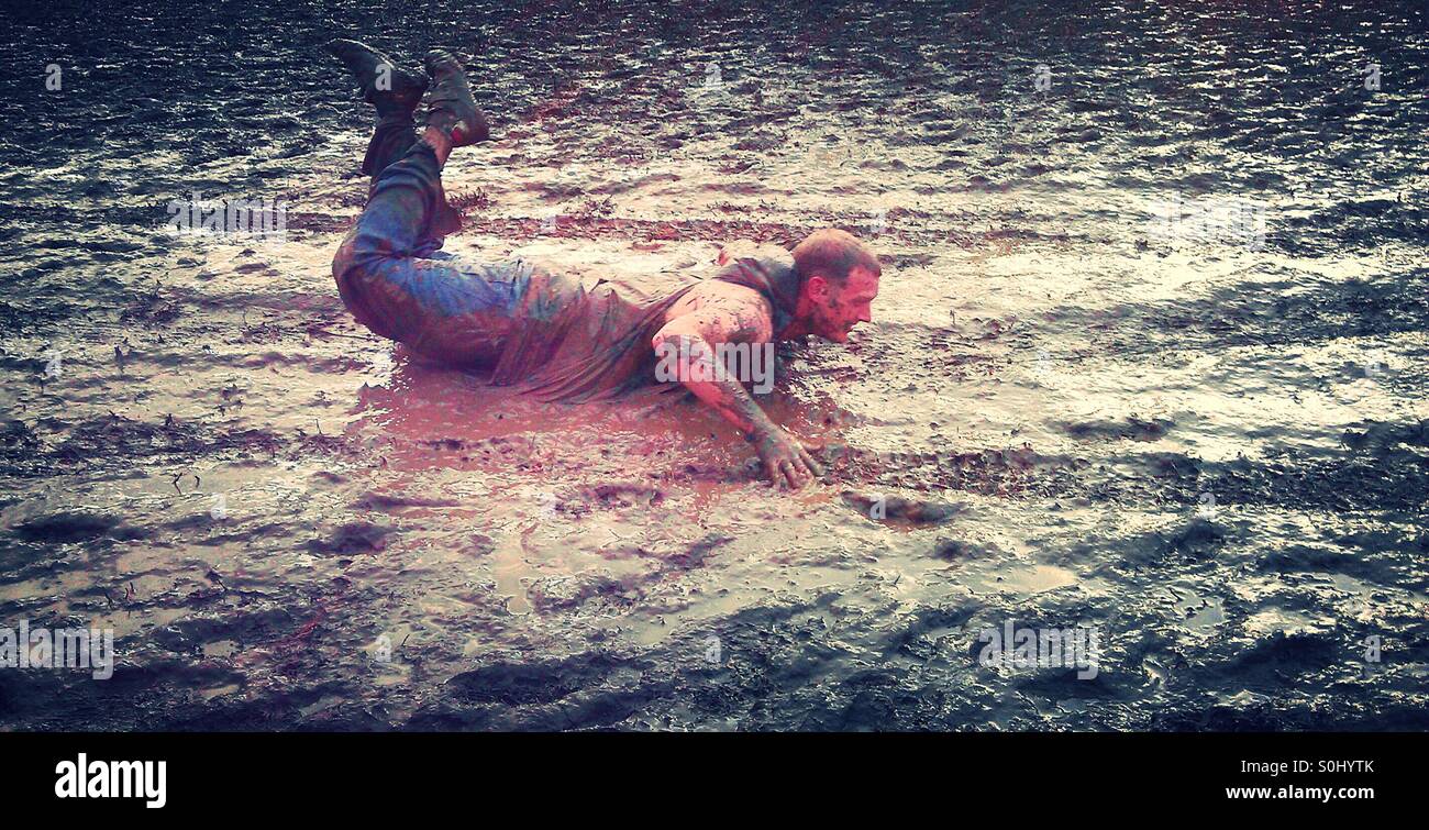 Man sliding through mud at festival - Smartphone Captured Stock Image