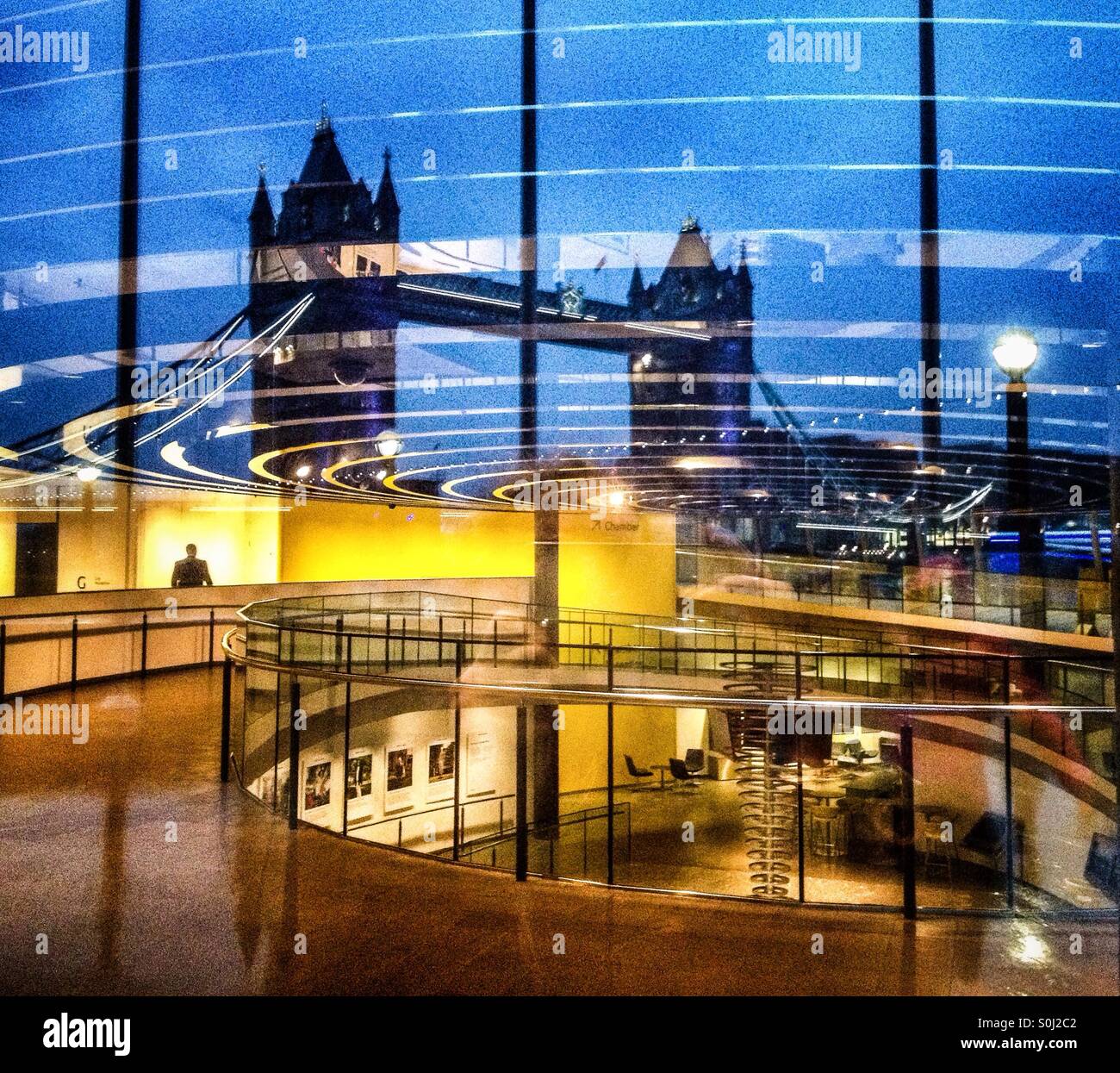 Tower Bridge is reflected in the window of London's City Hall at dusk - Smartphone Captured Stock Image