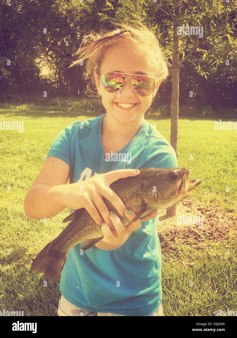 Young girl holding a Largemouth Bass she caught while fishing Stock Photo