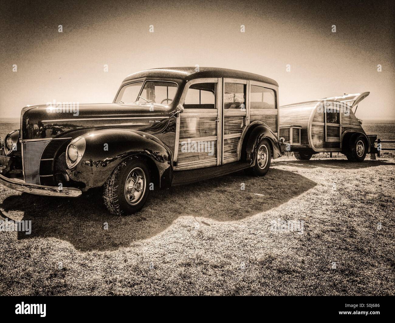 A 1940 Ford Deluxe Woodie towing a 1948 wooden teardrop camper trailer on the ocean at Santa Barbara, California USA Stock Photo