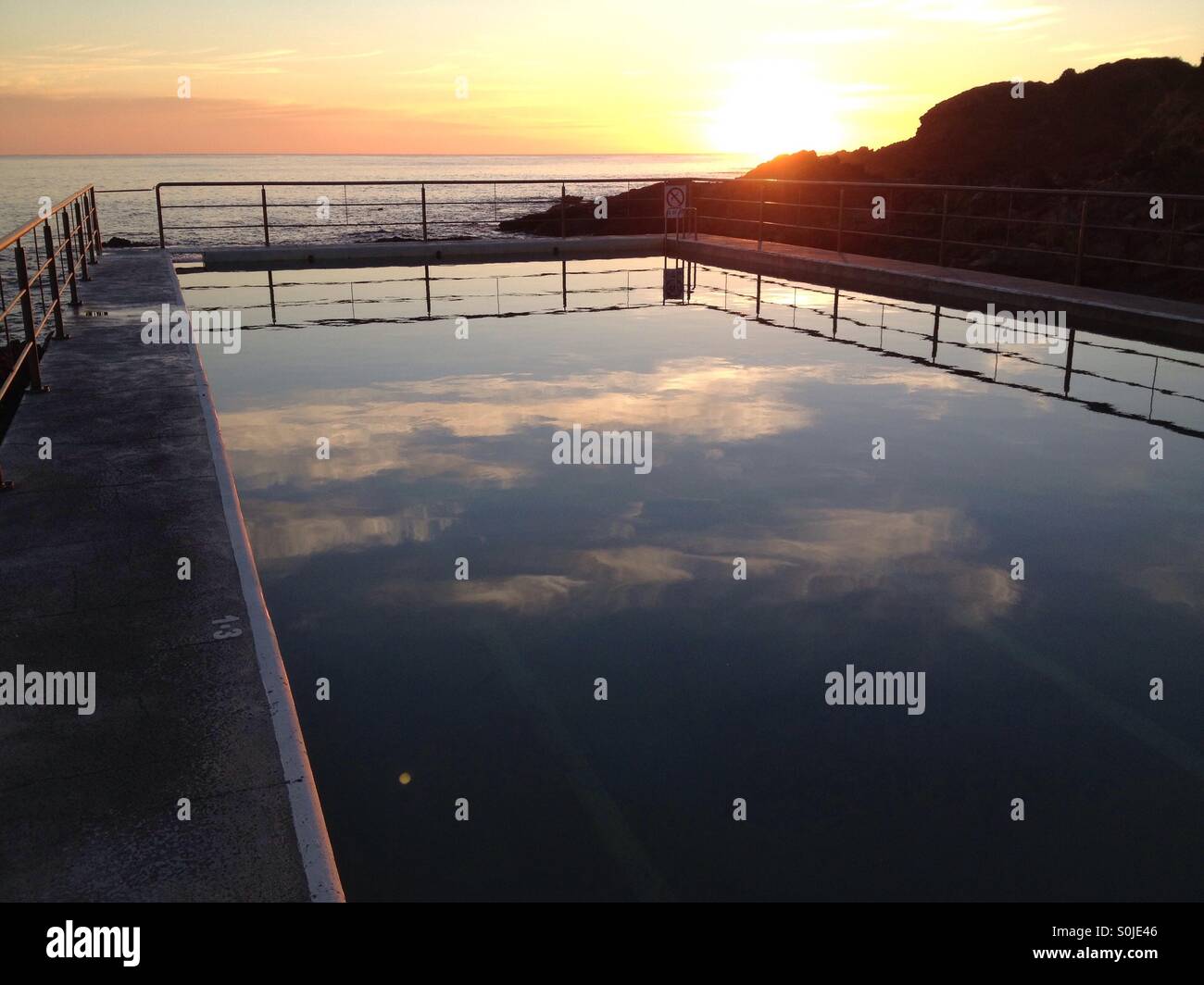 Reflections of morning clouds sail across this ocean pool in the early light of dawn - Smartphone Captured Stock Image