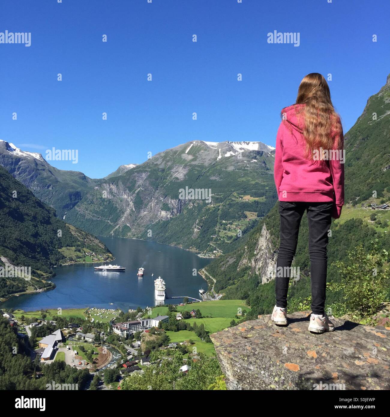Girl looking down at cruise ships visiting Geiranger, Norway Stock Photo