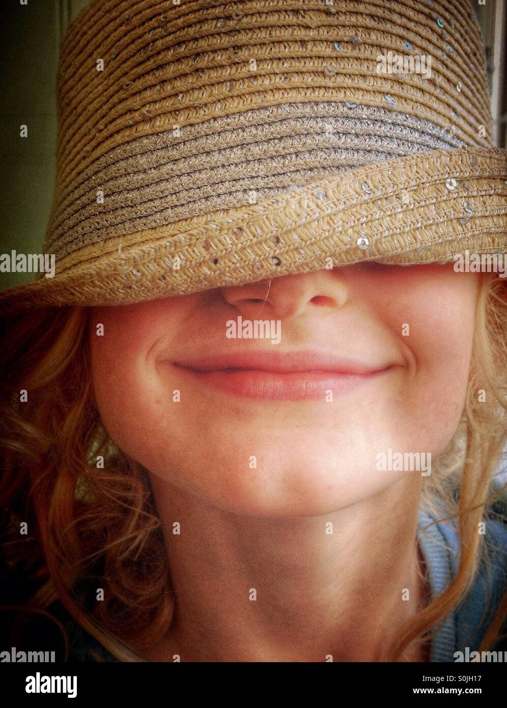 Young girl wearing hat over her eyes and smiling Stock Photo