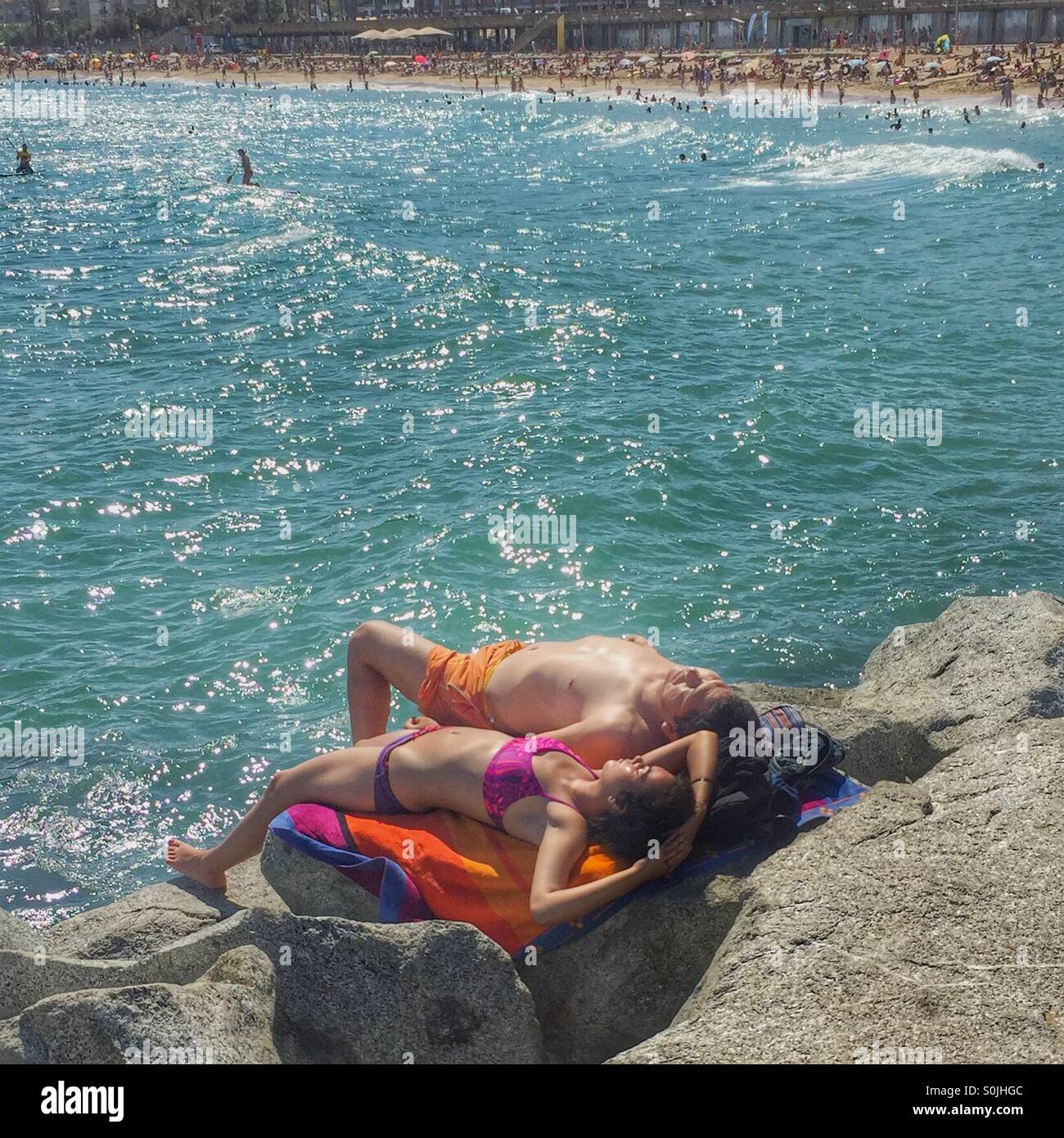 Man and women sunbathing on a rock Stock Photo