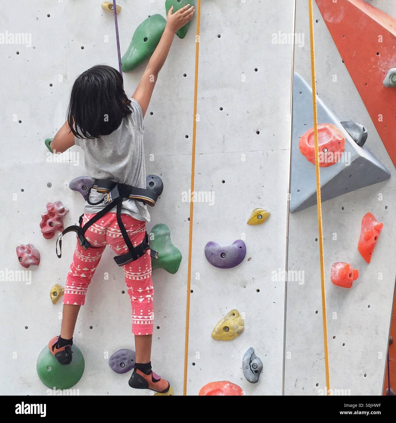 little girl climbing an indoor wall Stock Photo