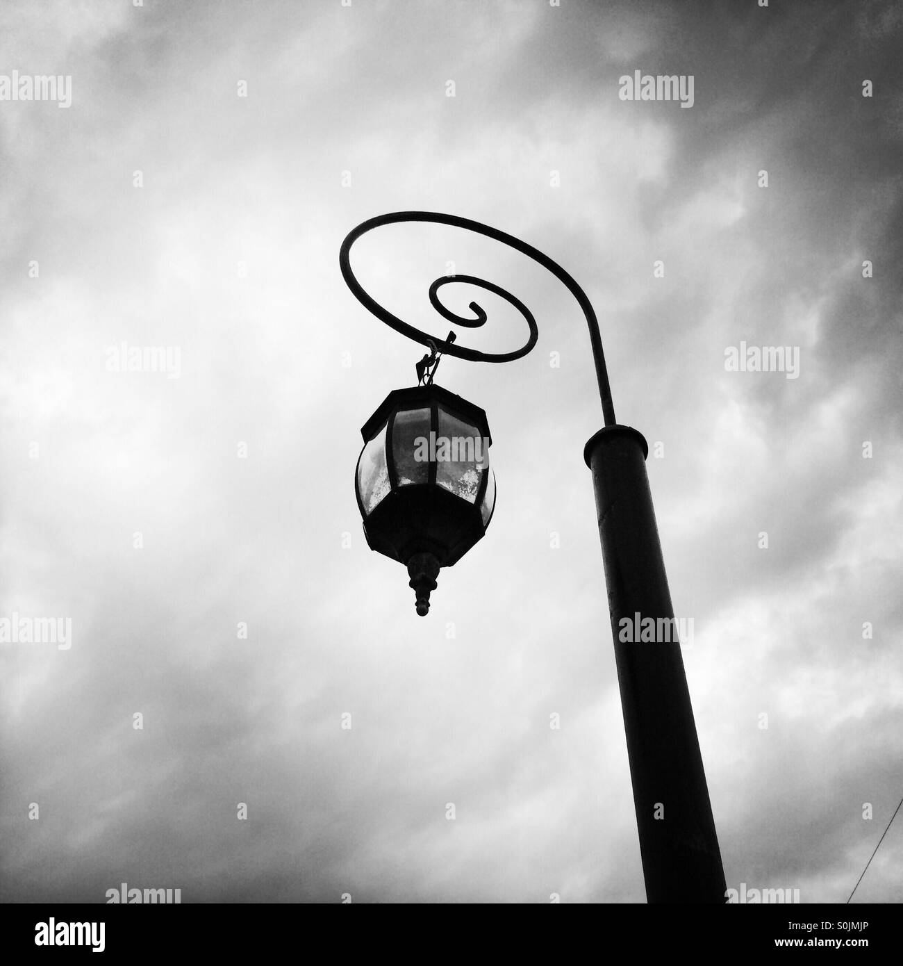Street lamp post with clouds in the background in black and white. Stock Photo