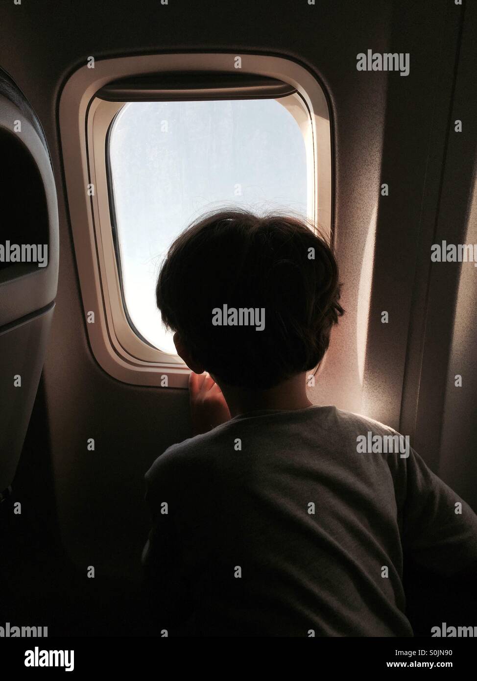 Boy silhouette looking out of an airplane window - Smartphone Captured Stock Image