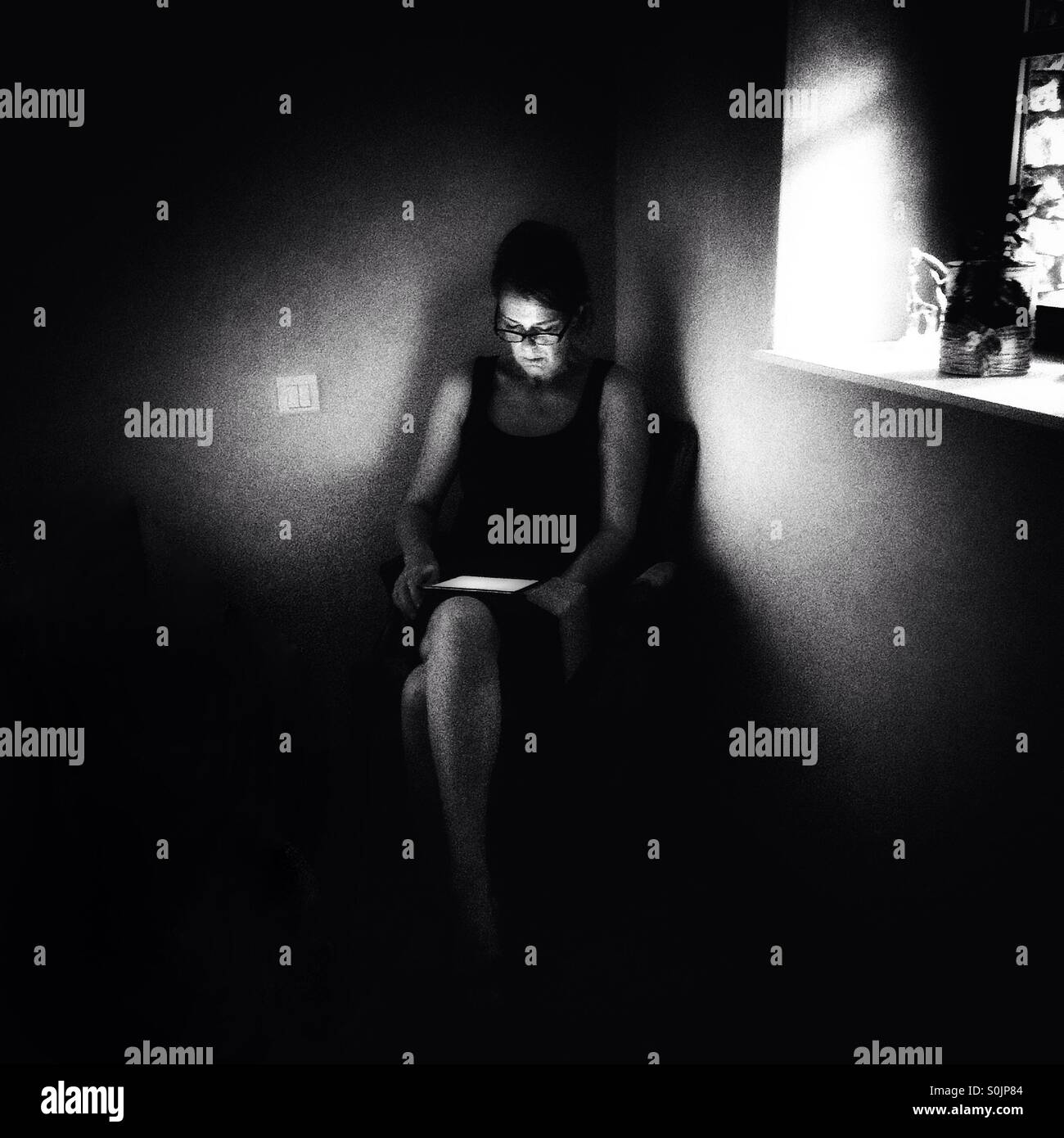 Woman using tablet in dimly lit room - Smartphone Captured Stock Image