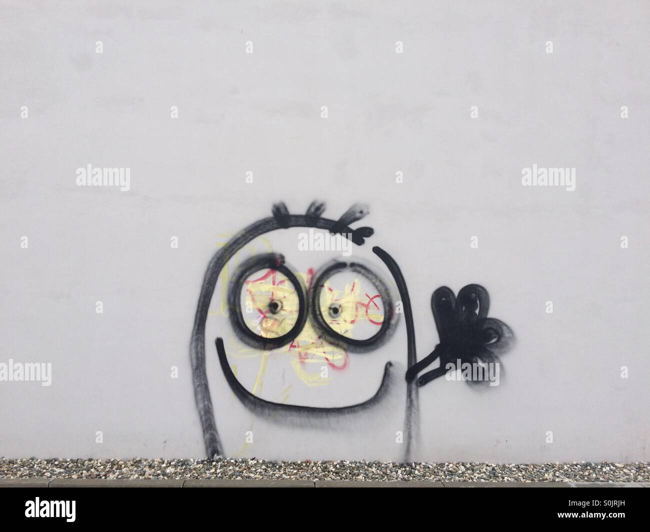 Street art, graffiti on a grey wall of a 'minion' lookalike cartoon, spotting Łódź, Poland Stock Photo